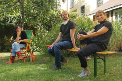 Die Künstler*innen Julia Neuhaus, Sebastian Meschenmoser und Nadia Budde sitzen im LesArt-Garten.