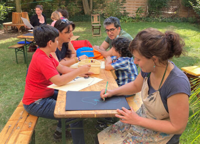 Die Künstlerin Iris Anemone Paul beim Zeichnen mit Familien anlässlich eines Workshops zu AUSERLESENES im LesArt-Garten