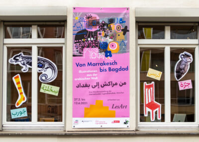 Außenfassade des LesArt-Hauses mit Banner und Fensterdekoration zur Ausstellung “Von Marrakesch bis Bagdad. Illustrationen aus der arabischen Welt”