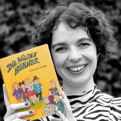 Anna Sphie Keil hält das Buch “Die Wilden Hühner” von Cornelia Funke neben ihr Gesicht.