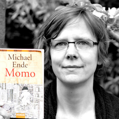 Annette Wostrak hält das Buch “Momo” von Michael Ende neben ihr Gesicht.