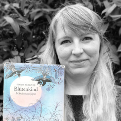 Franziska Bauer hält das Buch “Blütenkind. Märchen aus Japan” von Edith Bergner neben ihr Gesicht.