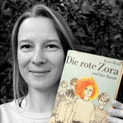 Sarah Möser hält das Buch “Die rote Zora” von Kurt Held neben ihr Gesicht.