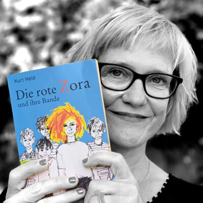 Sofie Hüsler hält das Buch “Die rote Zora” von Kurt Held neben ihr Gesicht.