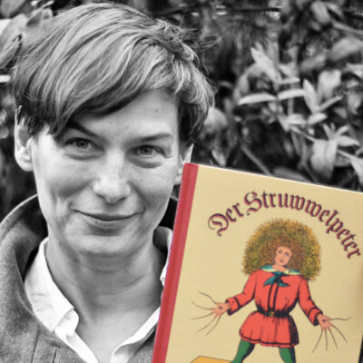 Sylvia Habermann hält das Buch “Struwwelpeter” von Heinrich Hoffmann neben ihr Gesicht.