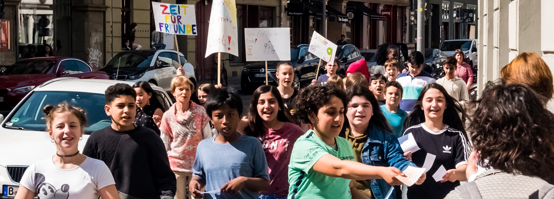 LesArt-Veranstaltung auf den Straßen Berlins: Jugendliche verteilen Flugblätter an Passant*innen und halten Demonstrationsschilder in die Luft.